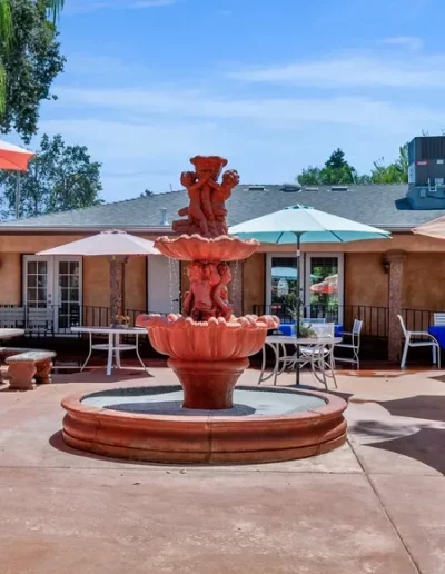 Outdoor area at Glory Days Senior Living with a water feature, comfortable tables for residents, and a welcoming environment.