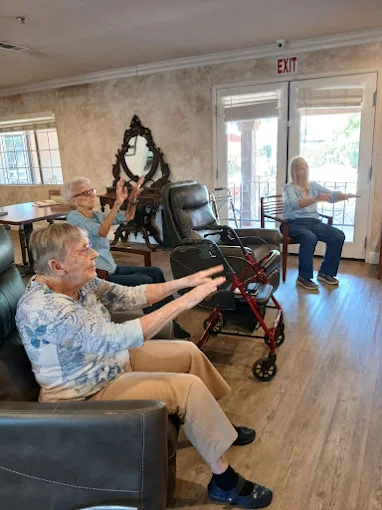 Residents participating in an indoor group exercise or engaging activity session, promoting cognitive function and well-being for seniors in Visalia.