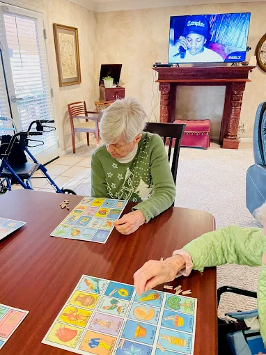 Senior resident focused on playing a card or board game indoors, demonstrating engaging activities for cognitive health in memory care.