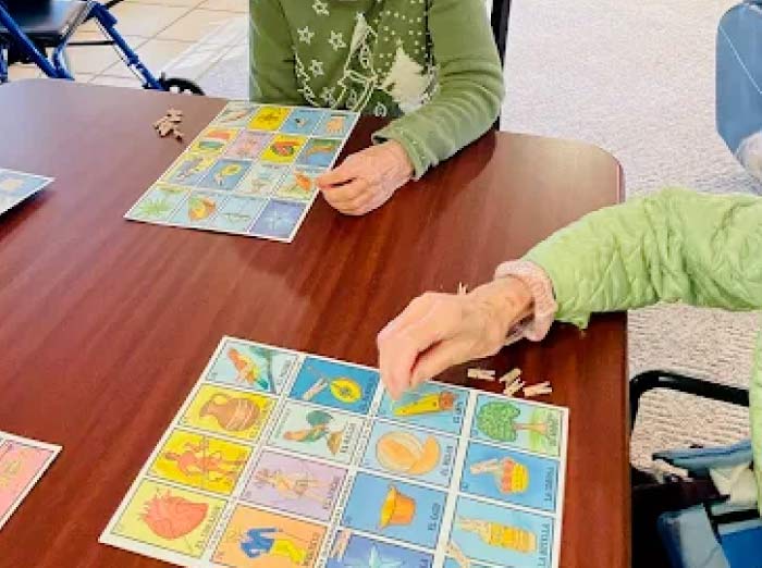 Close-up of residents' hands engaging in cognitive stimulation and social interaction by playing a colorful picture matching game at Glory Days memory care.